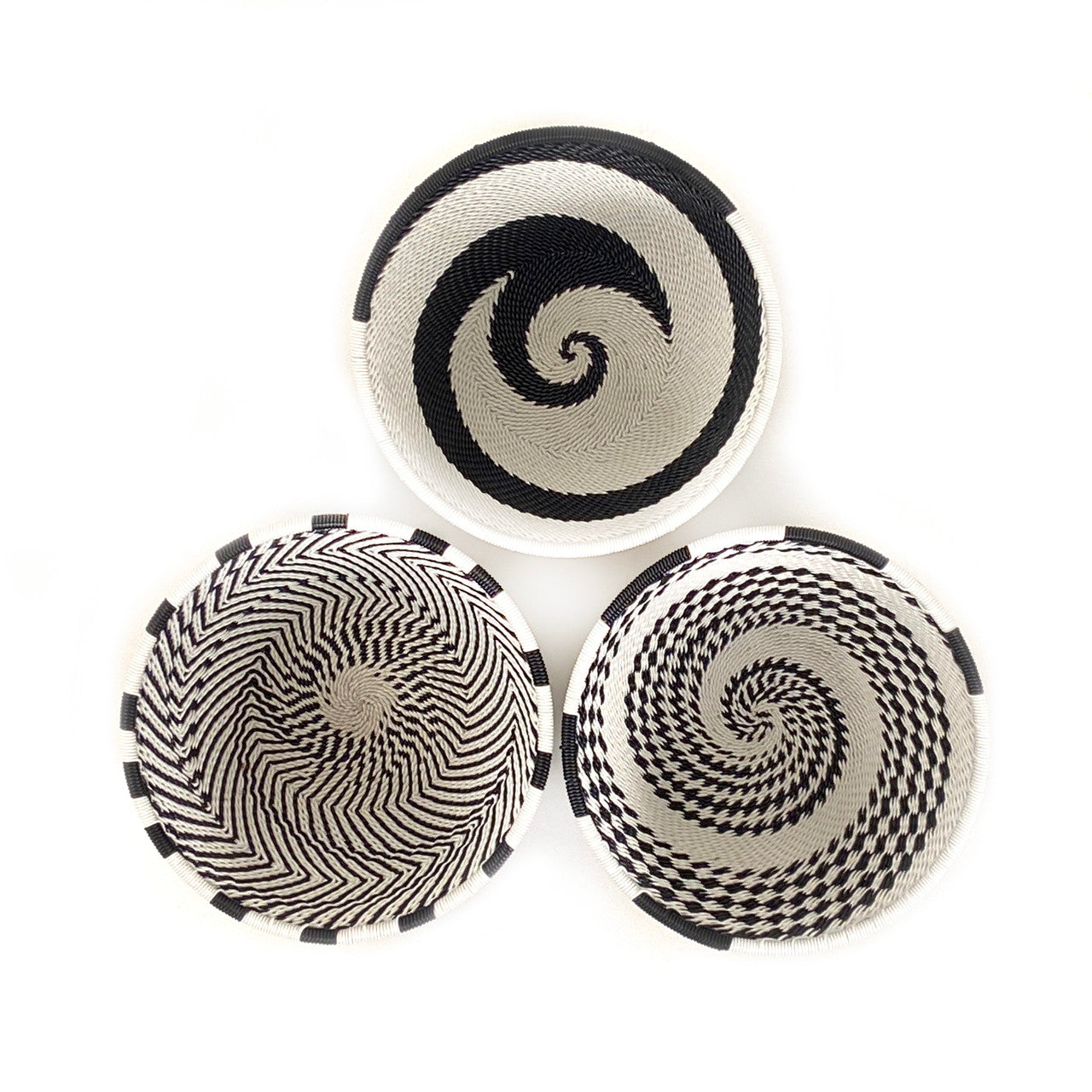 Black and white small bowls woven out of discarded telephone wire.