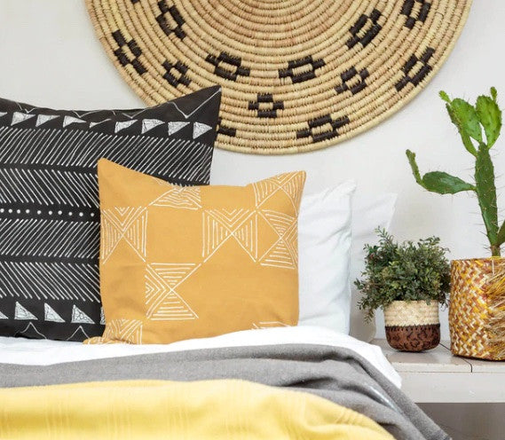 mustard matika pillow on a bed with other pillows