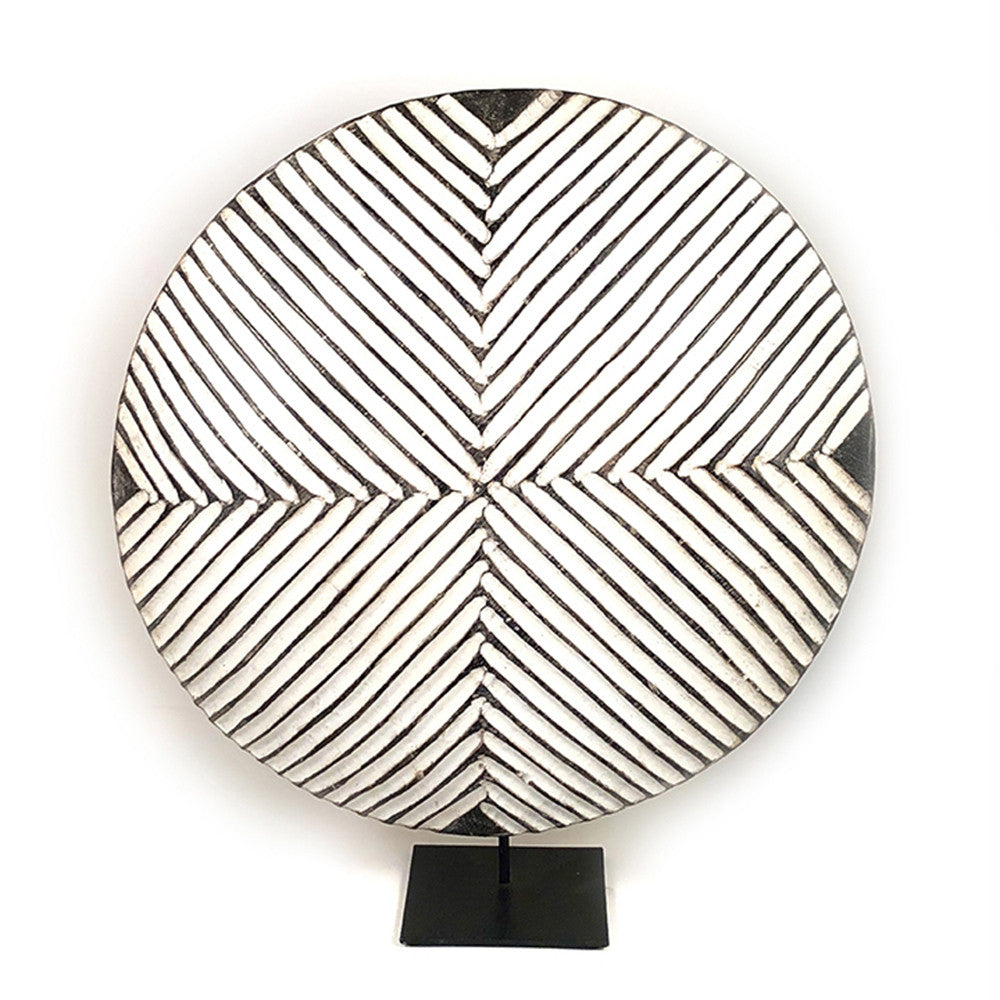 Round wooden Bamileke shield mounted with geometric pattern on a stand.